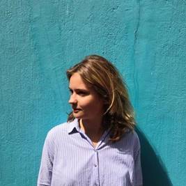 A person standing in front of a blue wall
Description automatically generated
